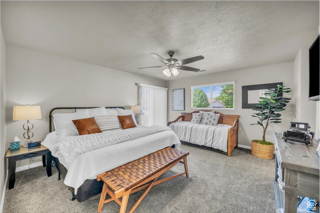 Bedroom featuring carpet, a ceiling fan, and a textured ceiling