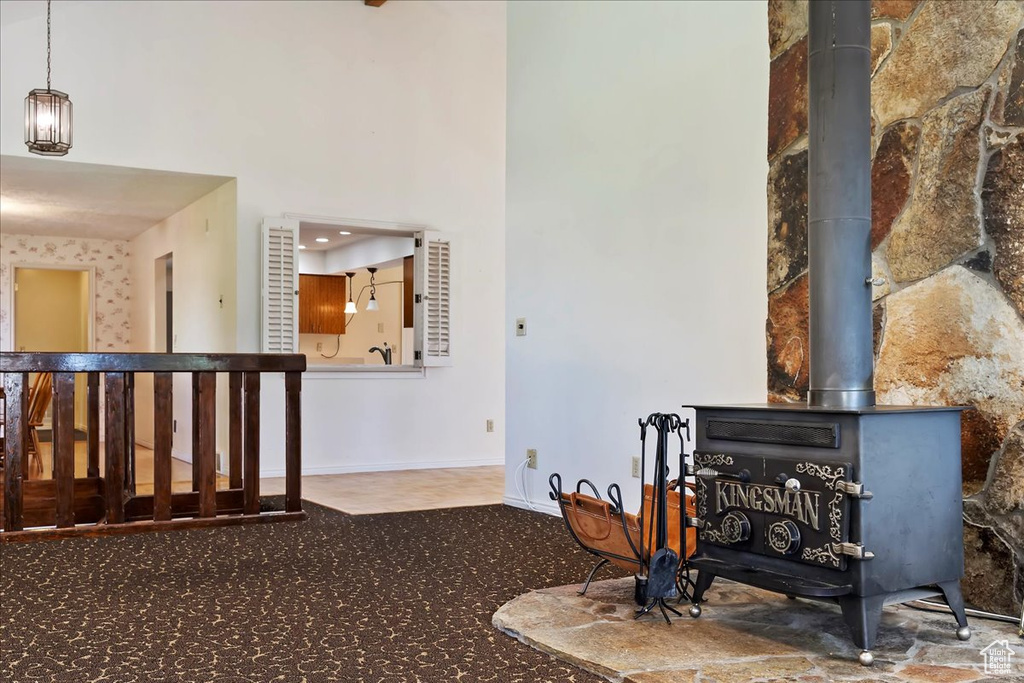 Living area with a wood stove, carpet floors, and a towering ceiling