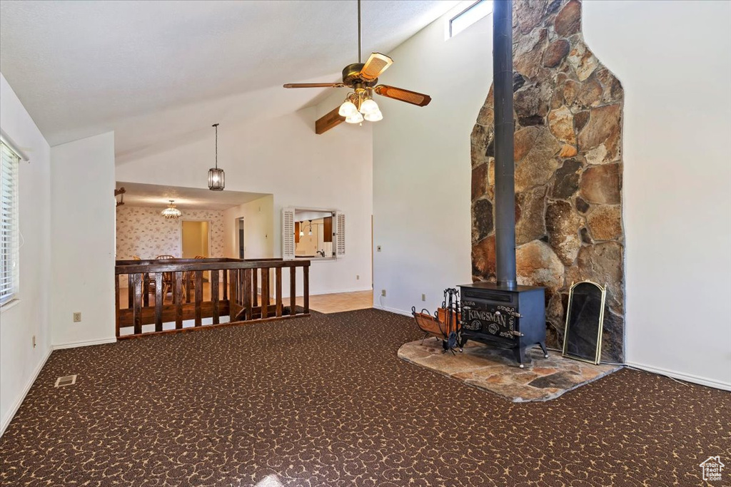 Carpeted living room featuring a wood stove, a ceiling fan, and high vaulted ceiling