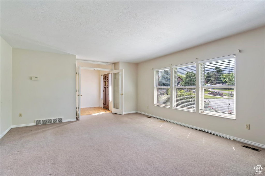 Carpeted empty room featuring baseboards and a textured ceiling