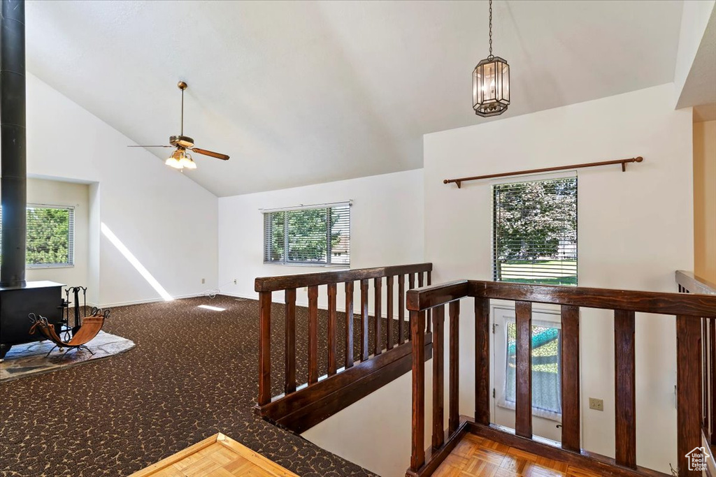 Staircase featuring a wood stove, healthy amount of natural light, ceiling fan, and high vaulted ceiling