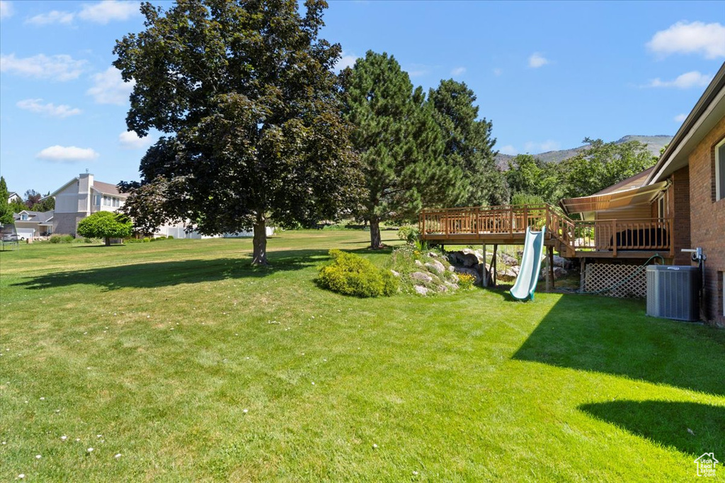 View of green lawn featuring a deck with mountain view