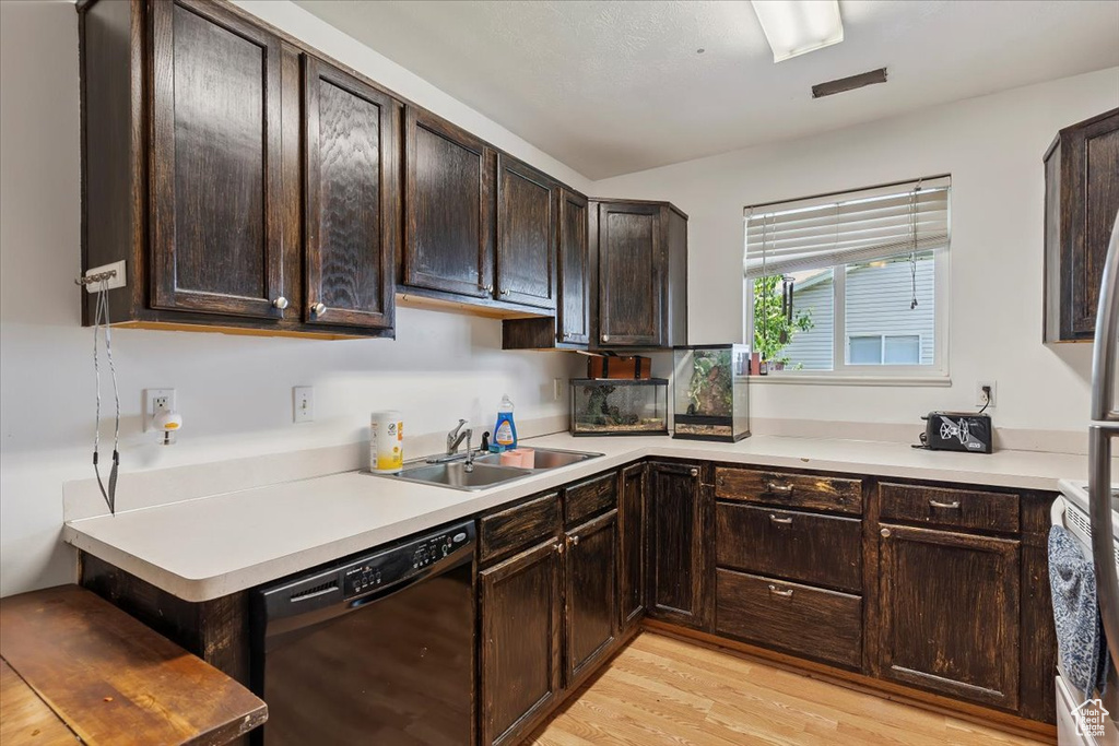 Kitchen with dishwasher, dark brown cabinets, light wood finished floors, and light countertops
