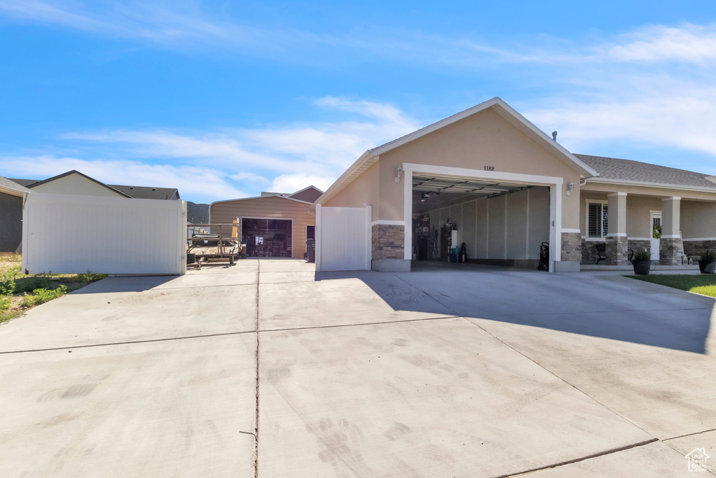 View of front of home with stucco siding, driveway, stone siding, and a garage