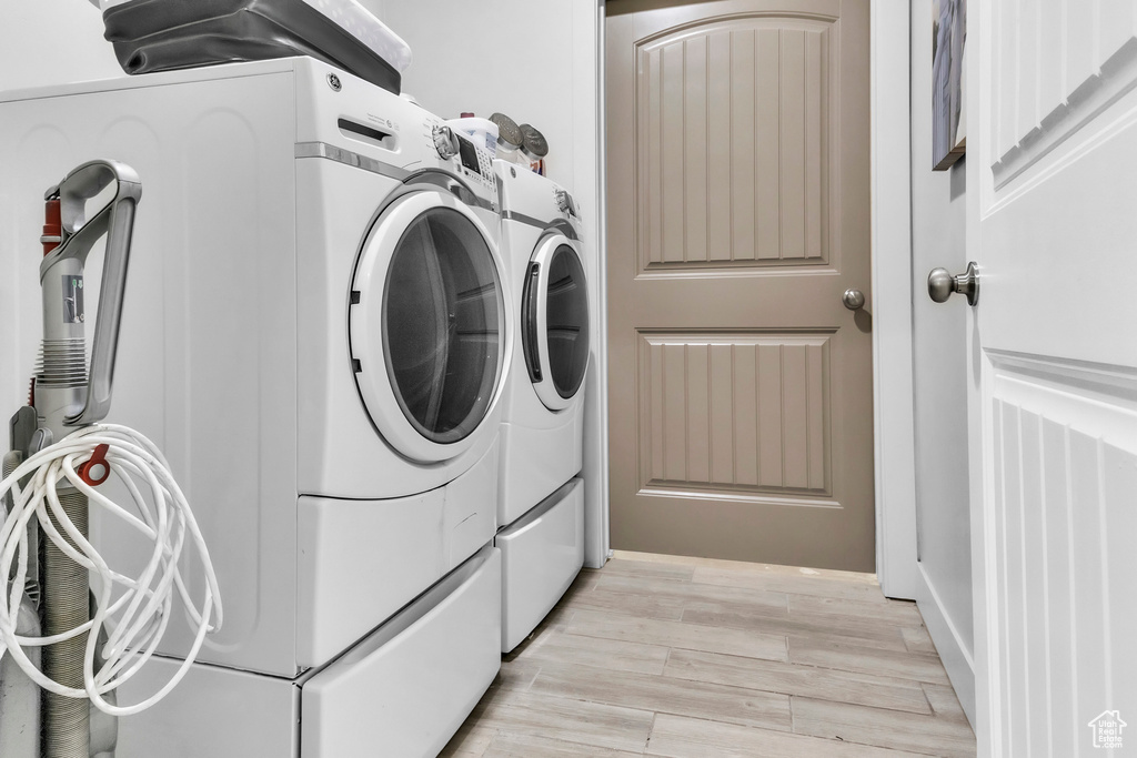 Washroom with independent washer and dryer and light wood-style floors