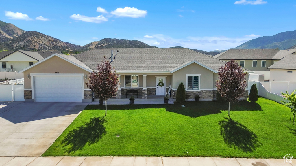View of front of house featuring stone siding, a porch, a mountain view, concrete driveway, and stucco siding