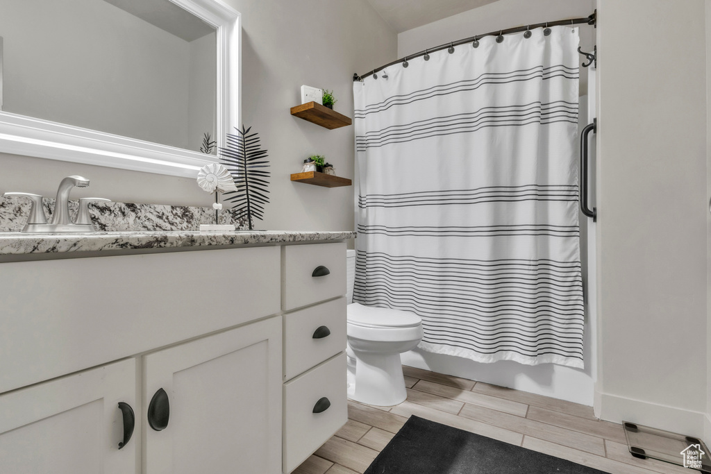 Bathroom featuring wood tiled floors, vanity, and shower / tub combo