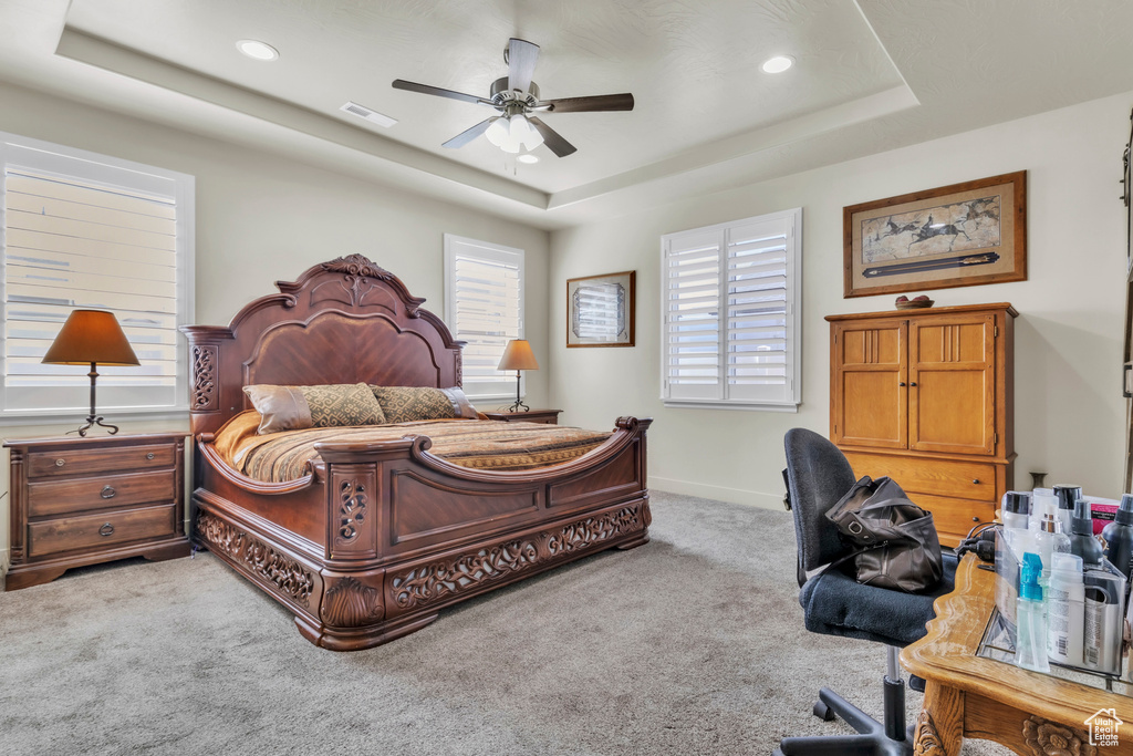Bedroom featuring a raised ceiling, light carpet, recessed lighting, and ceiling fan