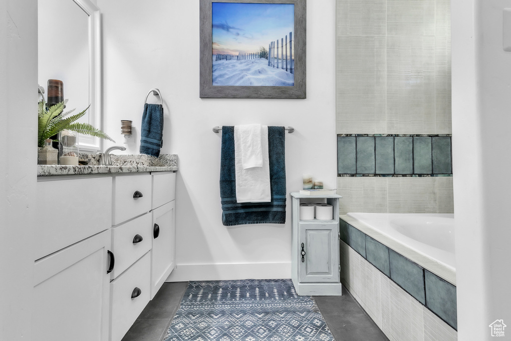 Full bath featuring vanity, tiled tub, and tile patterned floors