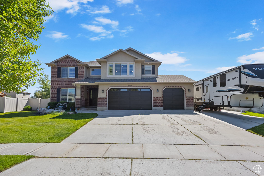 View of front facade featuring brick siding, a garage, concrete driveway, and stucco siding
