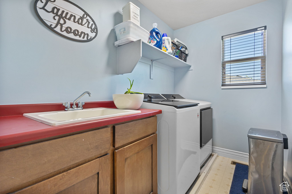 Laundry room with washing machine and clothes dryer, cabinet space, and light floors