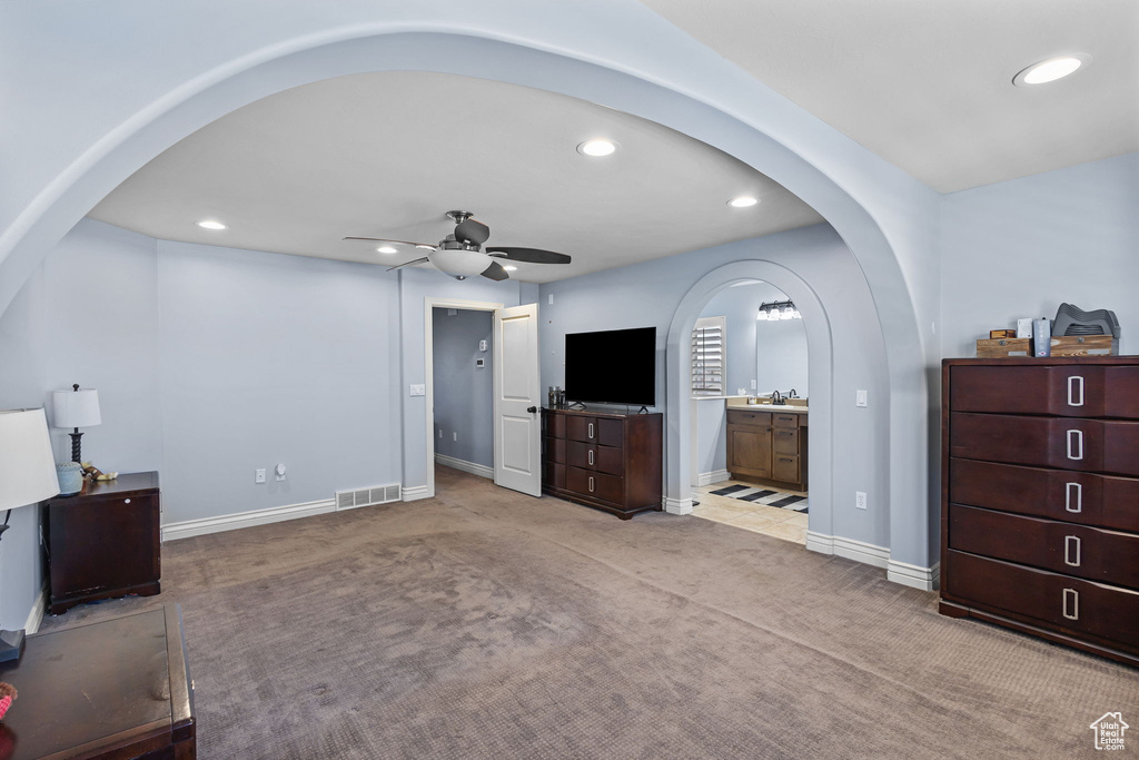 Living room with arched walkways, recessed lighting, ceiling fan, and carpet floors