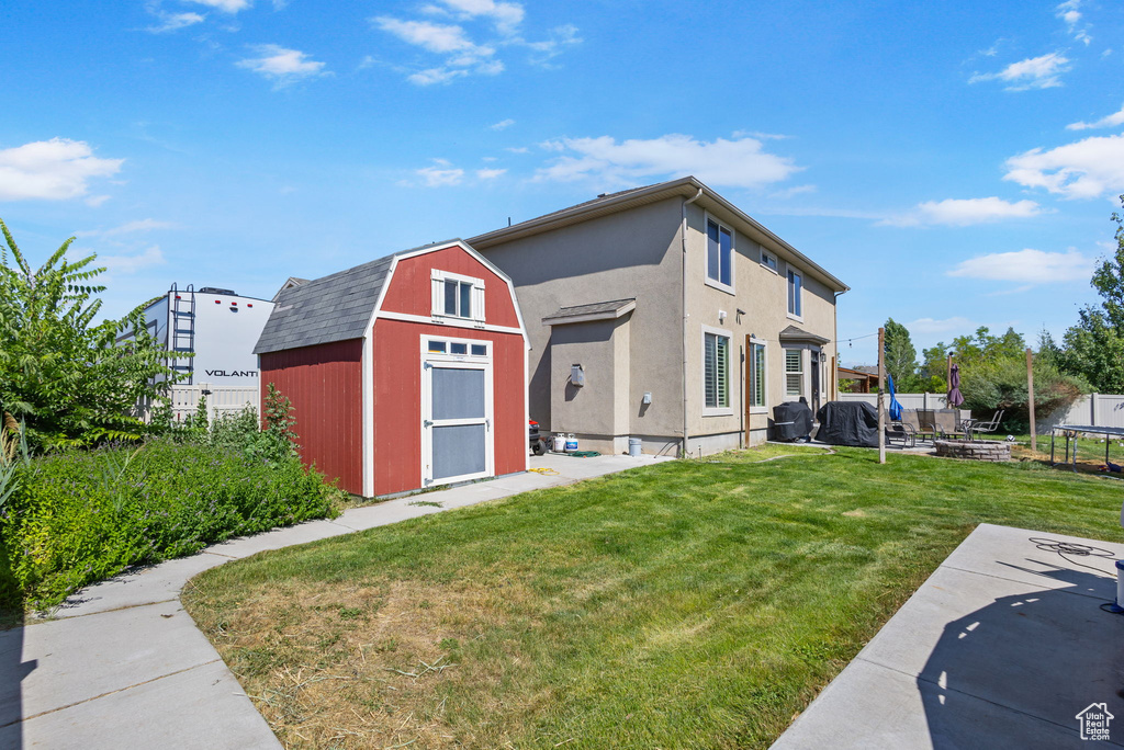Back of house with a storage shed, a gambrel roof, a patio, and a trampoline