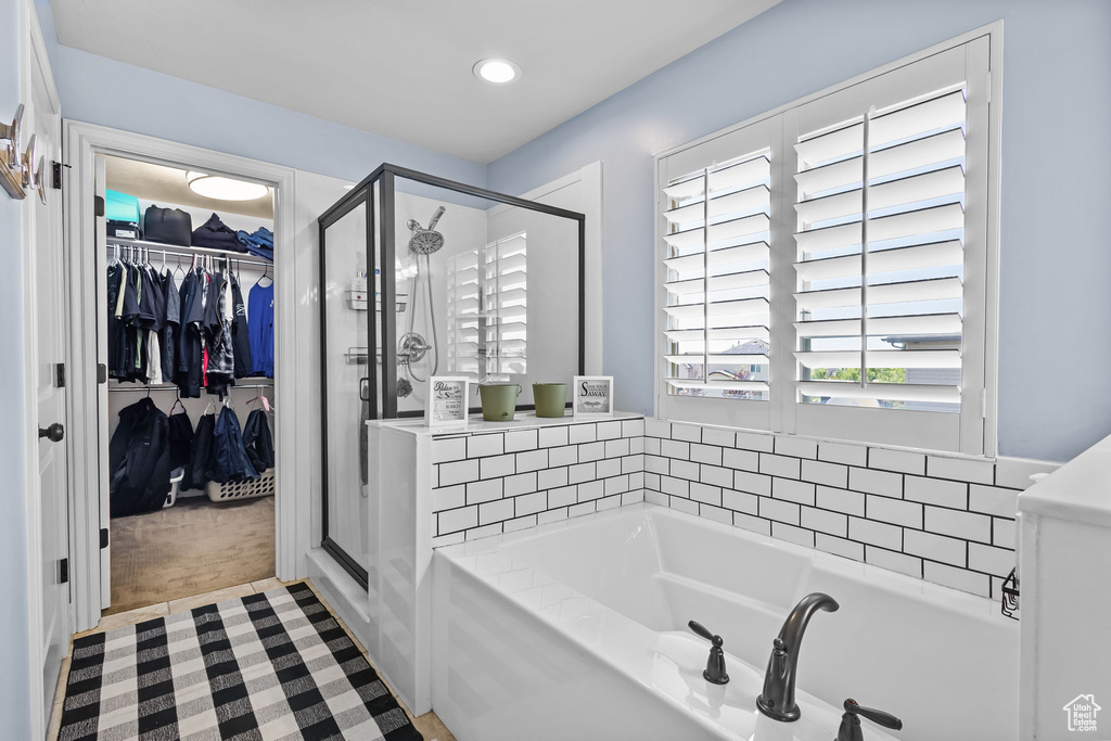 Bathroom featuring a stall shower, a bath, a spacious closet, and recessed lighting