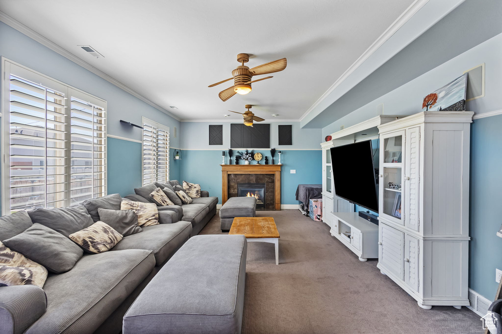 Living area with carpet, a ceiling fan, ornamental molding, and a lit fireplace