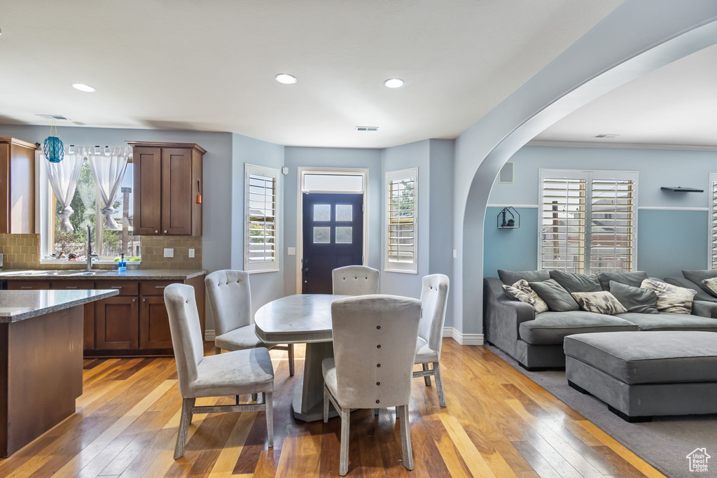 Dining room featuring light wood finished floors, arched walkways, healthy amount of natural light, and recessed lighting