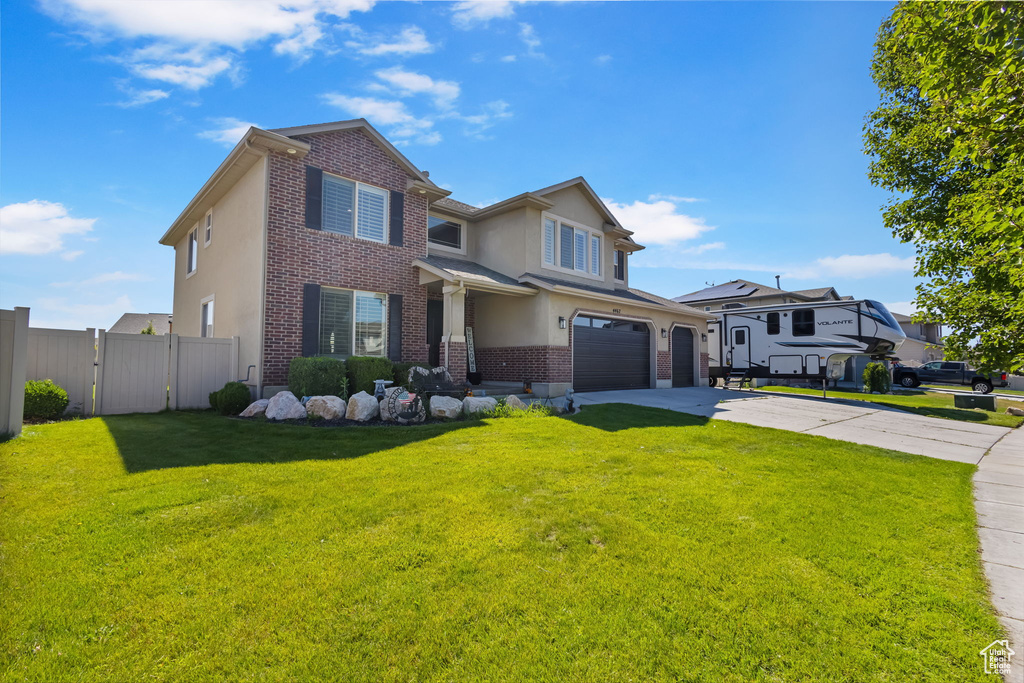 Traditional-style house with brick siding, a garage, concrete driveway, and stucco siding