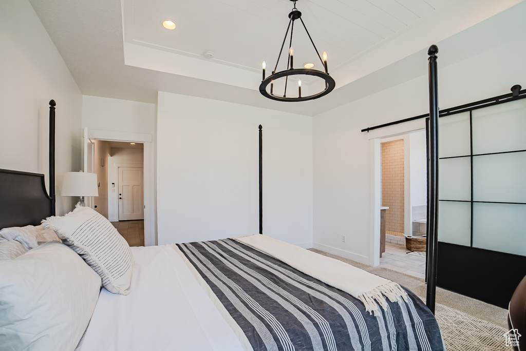 Bedroom with a raised ceiling, a chandelier, light colored carpet, recessed lighting, and ensuite bath