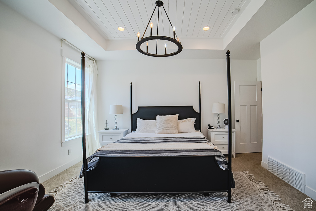 Bedroom with light colored carpet, a raised ceiling, a chandelier, and recessed lighting