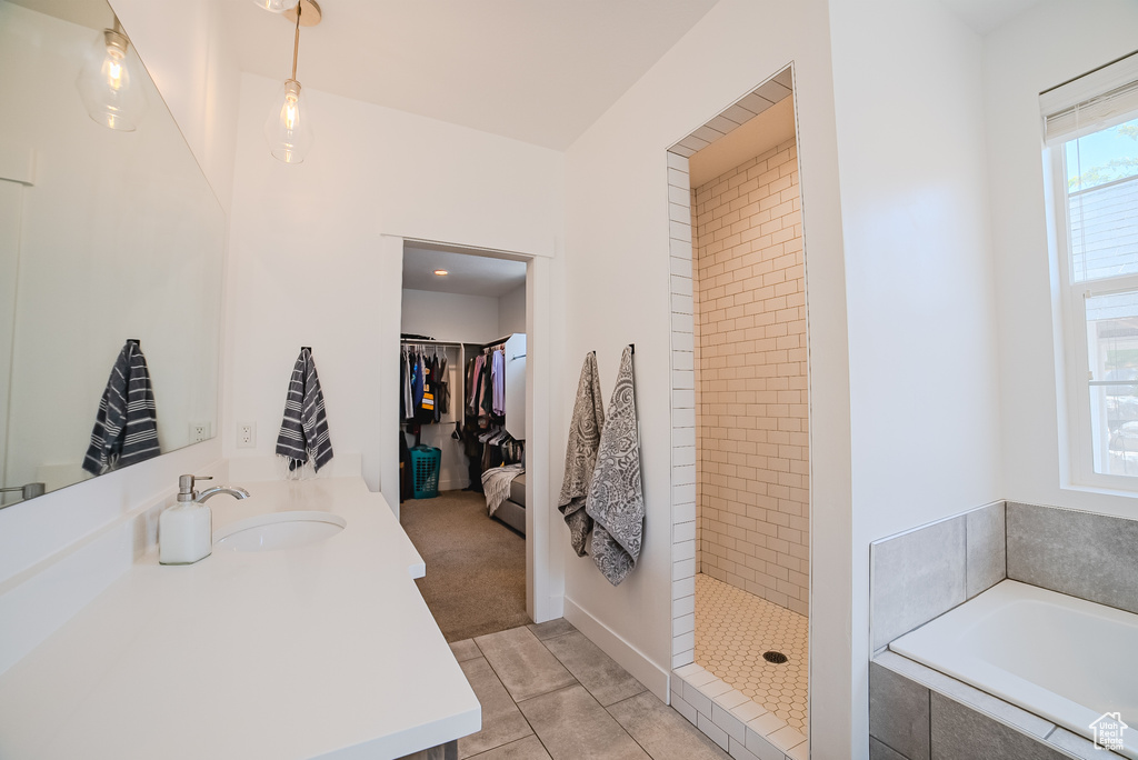 Bathroom featuring a garden tub, vanity, a tile shower, tile patterned floors, and a walk in closet
