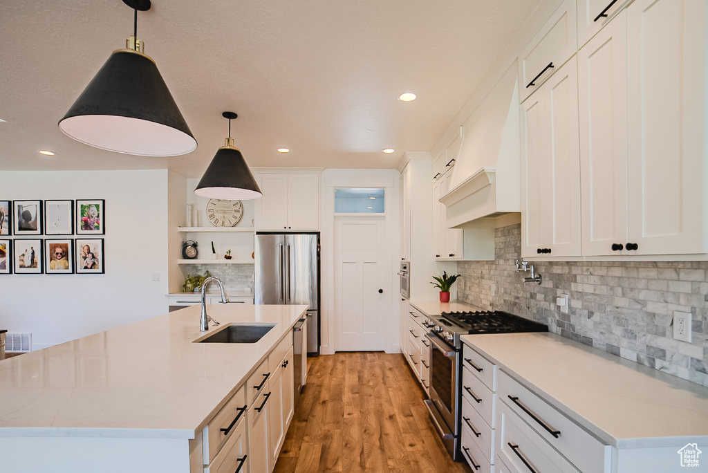 Kitchen with stainless steel appliances, open shelves, recessed lighting, an island with sink, and white cabinetry