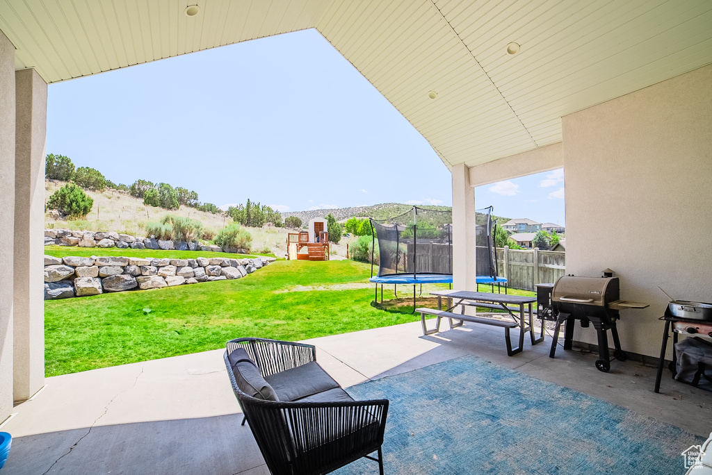View of patio / terrace featuring a trampoline, a playground, and a grill