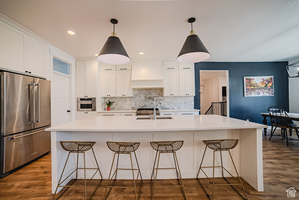 Kitchen with appliances with stainless steel finishes, premium range hood, tasteful backsplash, white cabinets, and recessed lighting
