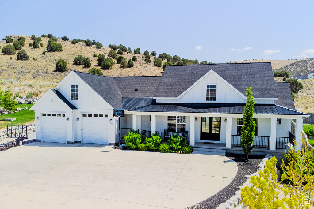 Modern farmhouse featuring board and batten siding, a porch, and a standing seam roof