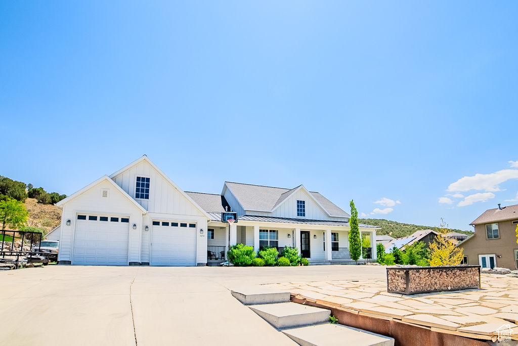 Modern farmhouse style home with board and batten siding, driveway, covered porch, and a standing seam roof