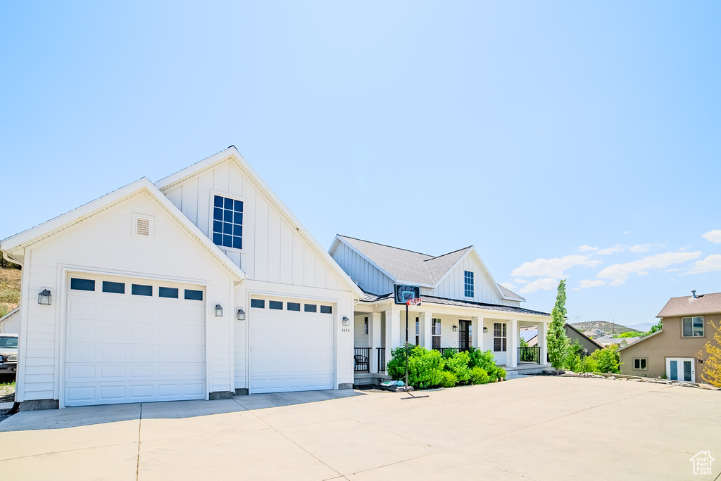 Modern inspired farmhouse with board and batten siding, covered porch, driveway, and a garage