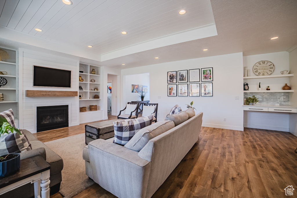 Living area with wood finished floors, recessed lighting, a large fireplace, and built in shelves