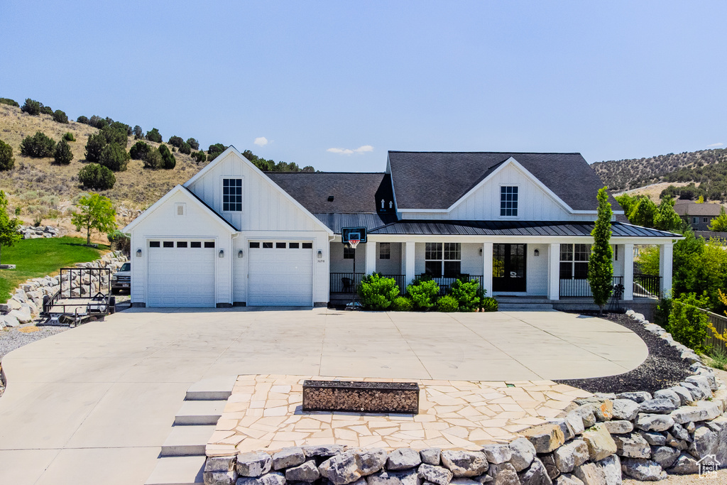 Modern farmhouse style home featuring board and batten siding, a standing seam roof, concrete driveway, and covered porch