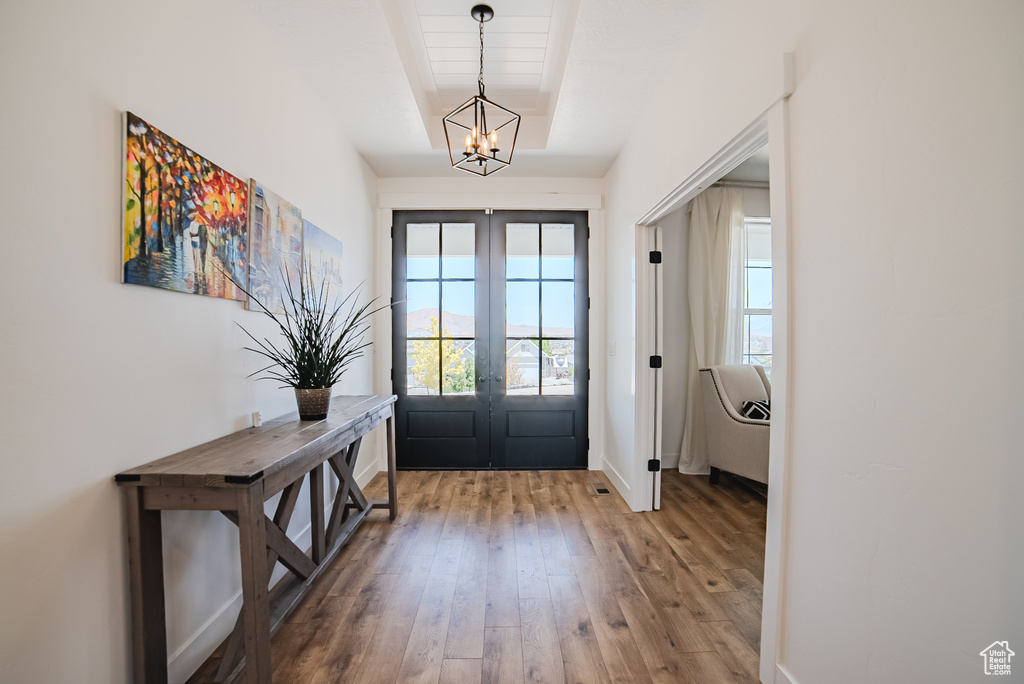 Entrance foyer with french doors, a chandelier, and wood-type flooring