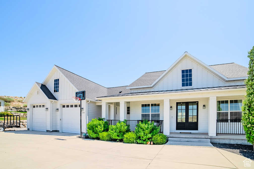 Modern inspired farmhouse with covered porch, board and batten siding, a garage, and concrete driveway