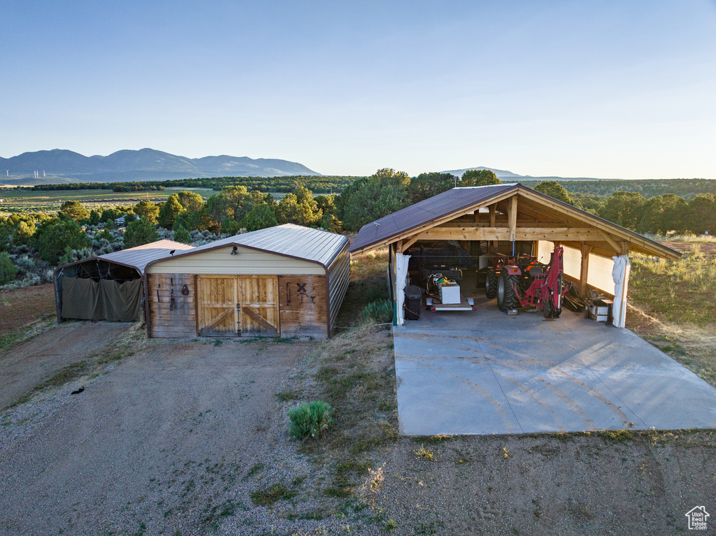 View of front of property featuring a carport, concrete driveway, an outdoor structure, and a mountain view