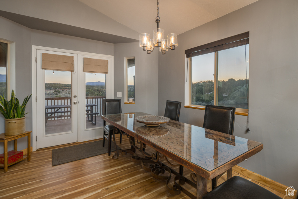 Dining area featuring a chandelier, light wood finished floors, lofted ceiling, and french doors