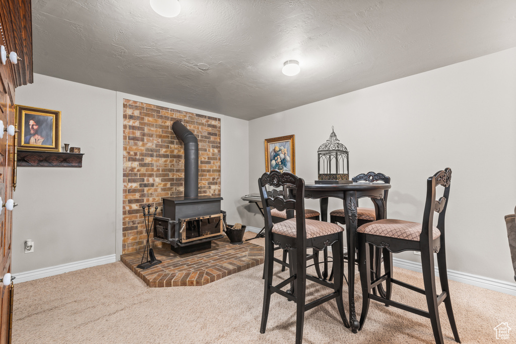 Dining space featuring carpet flooring, a wood stove, and a textured ceiling