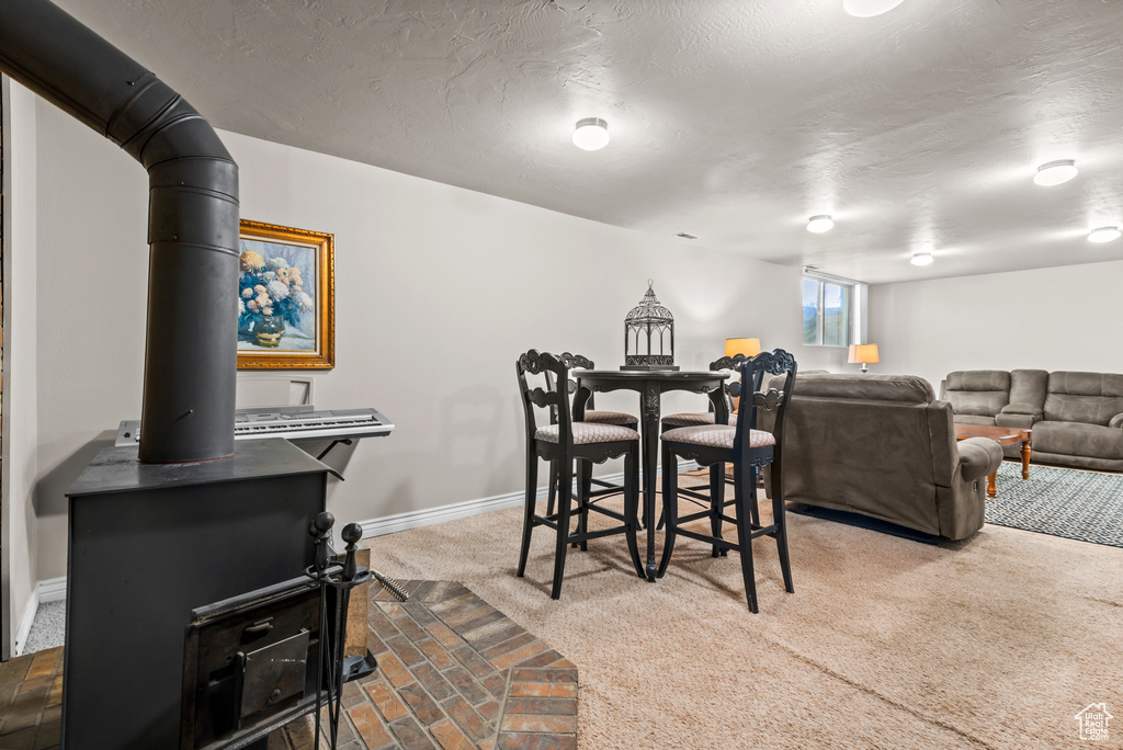 Carpeted dining space with baseboards and a wood stove