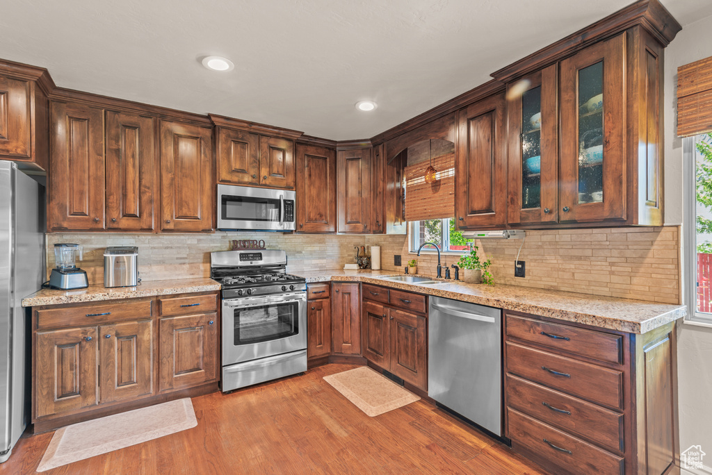 Kitchen featuring stainless steel appliances, wood finished floors, healthy amount of natural light, backsplash, and recessed lighting