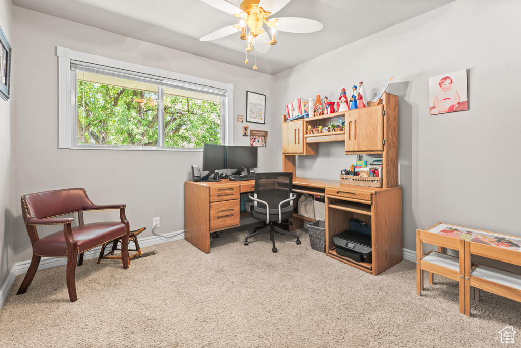 Home office with light carpet and a ceiling fan