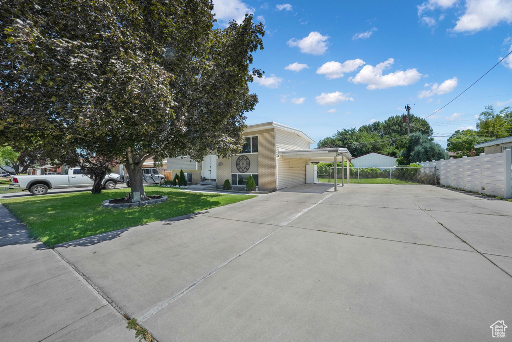 View of front facade with driveway, a carport, and brick siding
