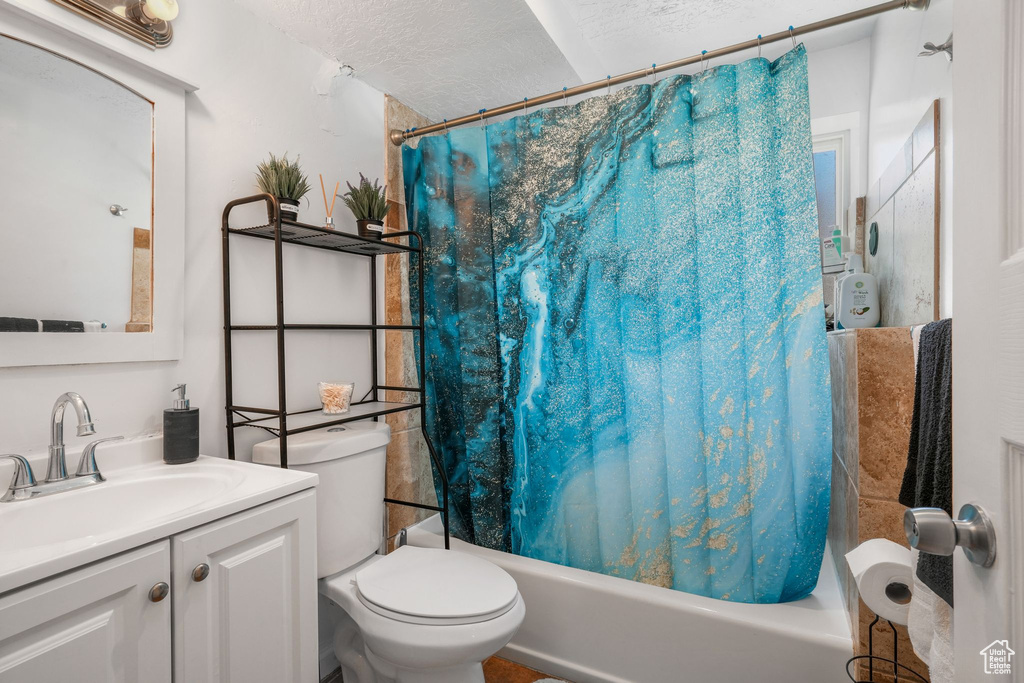 Full bath featuring shower / tub combo with curtain, vanity, and a textured ceiling