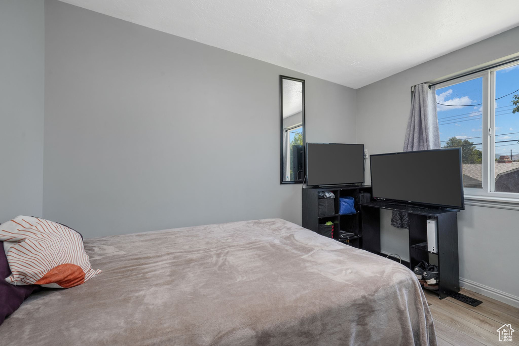 Bedroom with light wood-style flooring and multiple windows