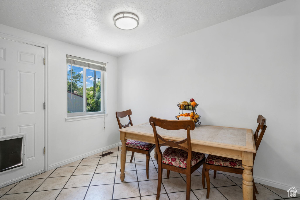 Dining area with a textured ceiling and light tile patterned floors
