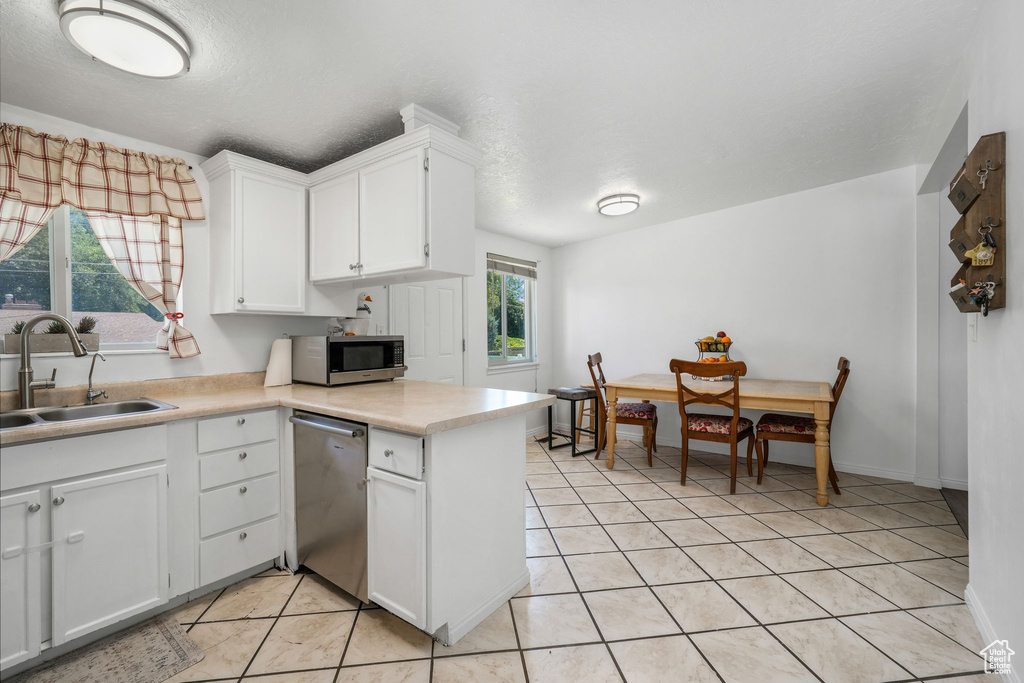 Kitchen with stainless steel appliances, white cabinetry, light countertops, and light tile patterned floors