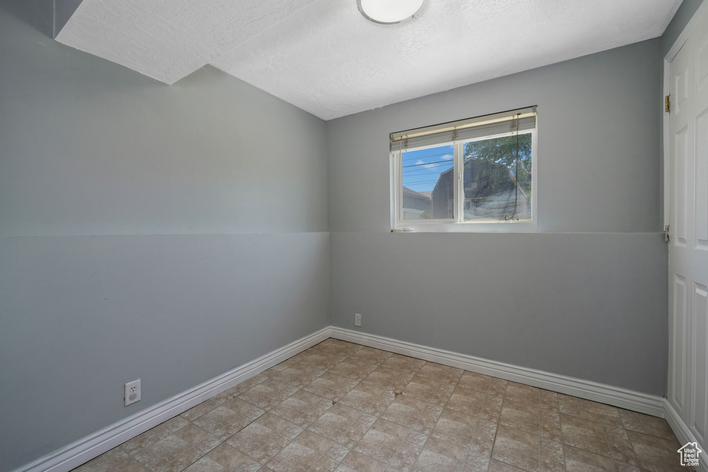 Spare room with a textured ceiling and stone finish floors