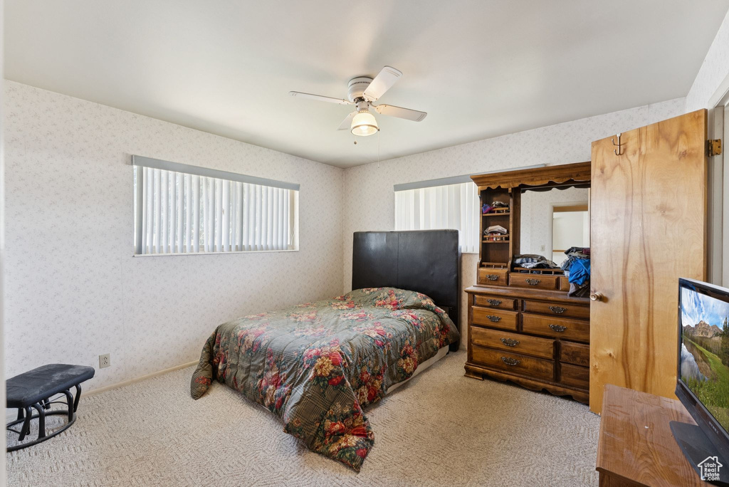 Carpeted bedroom with wallpapered walls and a ceiling fan