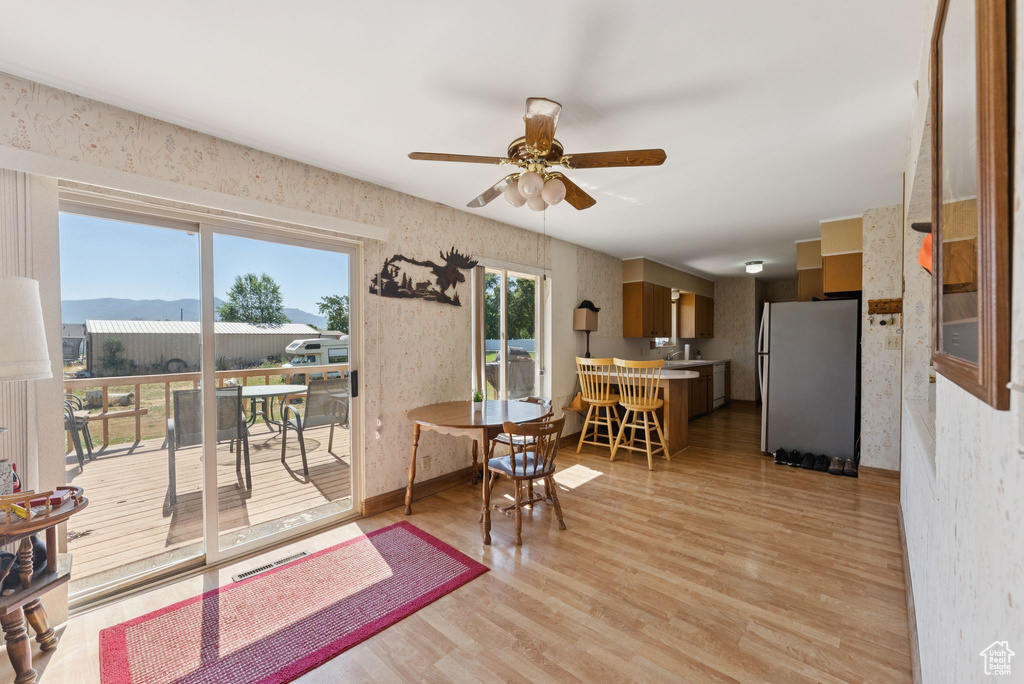 Dining area featuring wallpapered walls, ceiling fan, and light wood finished floors