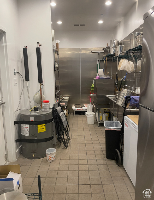 Kitchen with freestanding refrigerator, light tile patterned floors, strapped water heater, light countertops, and recessed lighting
