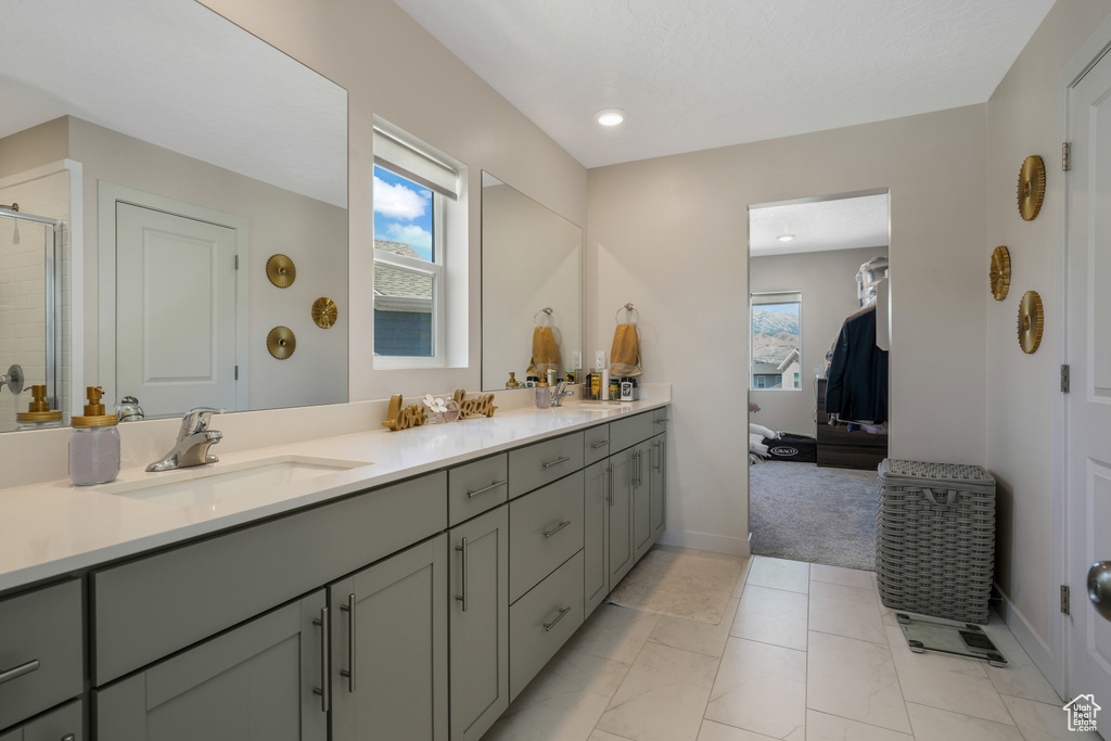 Ensuite bathroom with double vanity, healthy amount of natural light, a tile shower, and recessed lighting